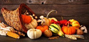 Thanksgiving cornucopia filled with autumn pumpkins and vegetables against a rustic dark wood background