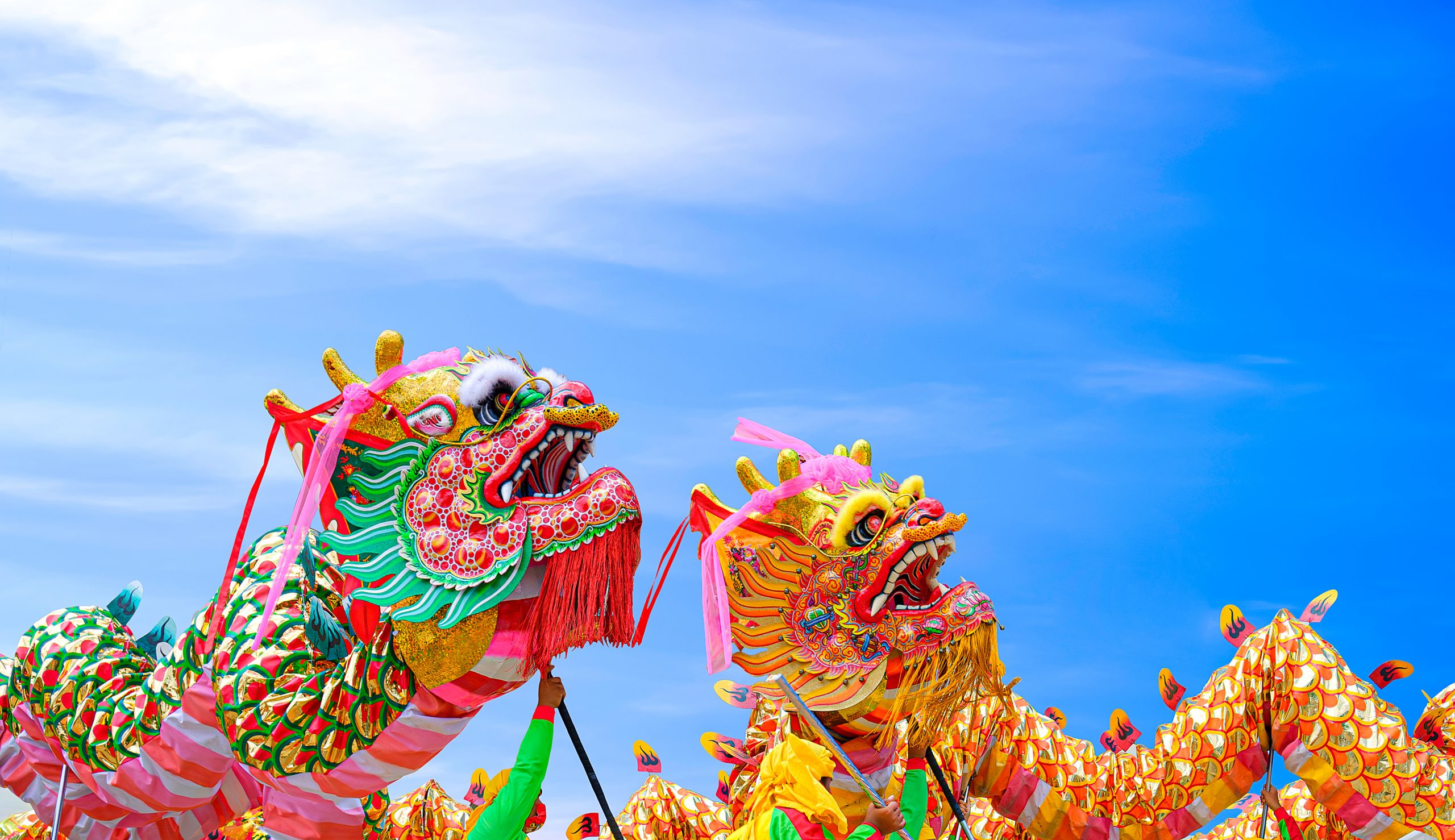 Two colorful Chinese dragon dance performances against blue sky background during Chinese New Year celebrate festival