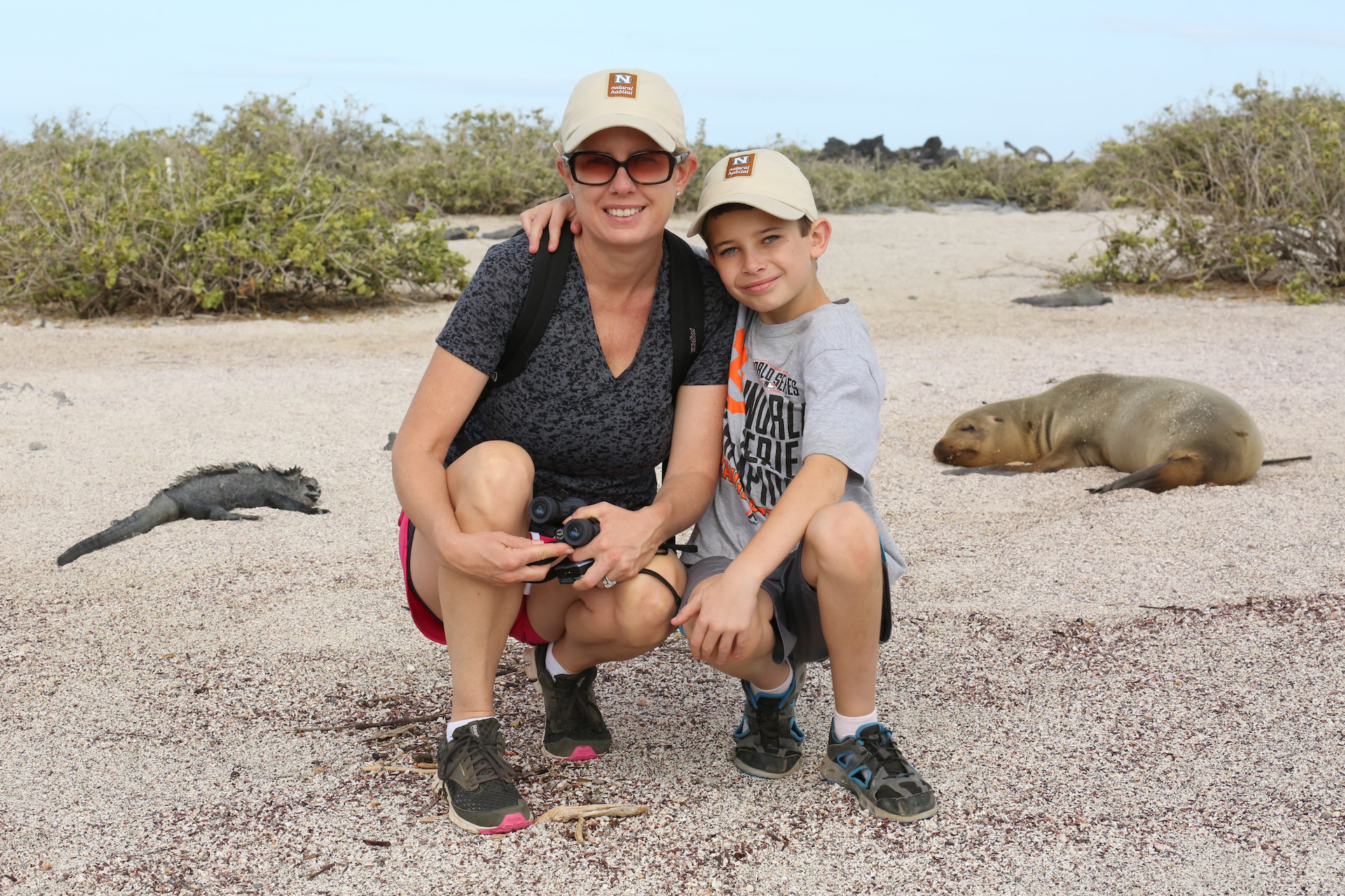 Nat Hab guests with marine iguana and Galapagos fur seal, Galapagos Islands, Ecuador. © Melissa Scott
