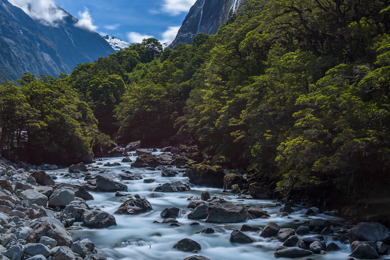 waterfall between way to landscape of high mountain glacier at milford sound, New Zealand