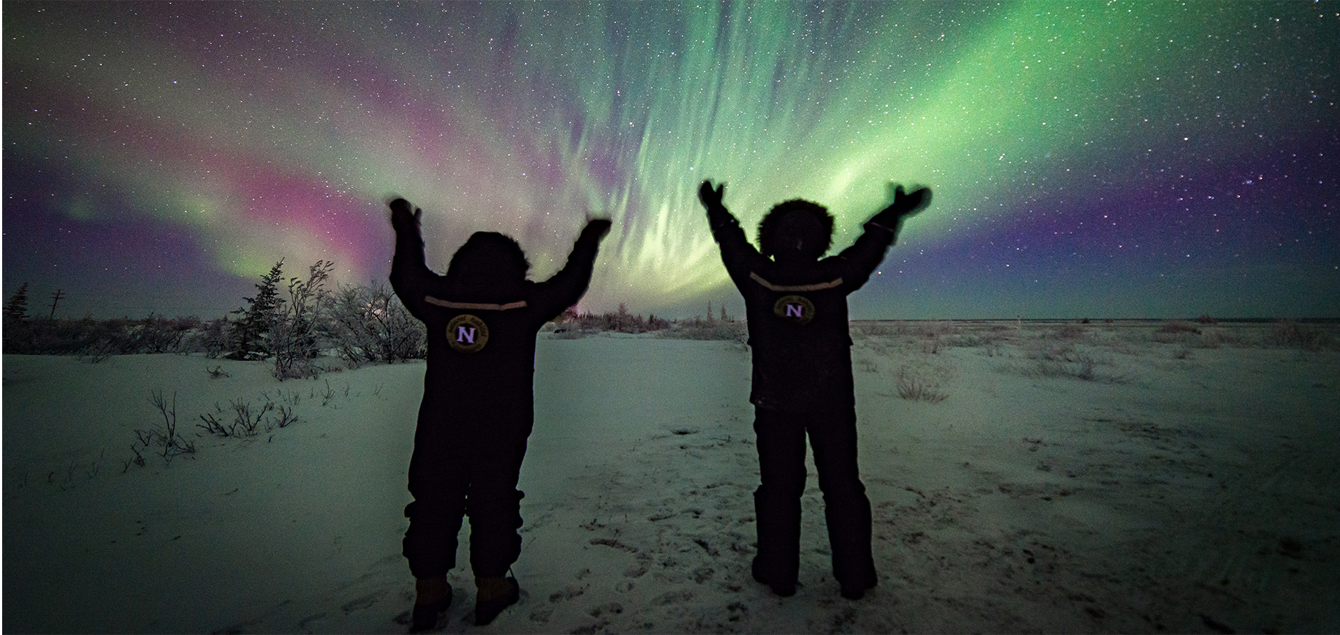 Two natural habitat adventures guests and guides celebrating and watching the northern lights in Churchill Canada