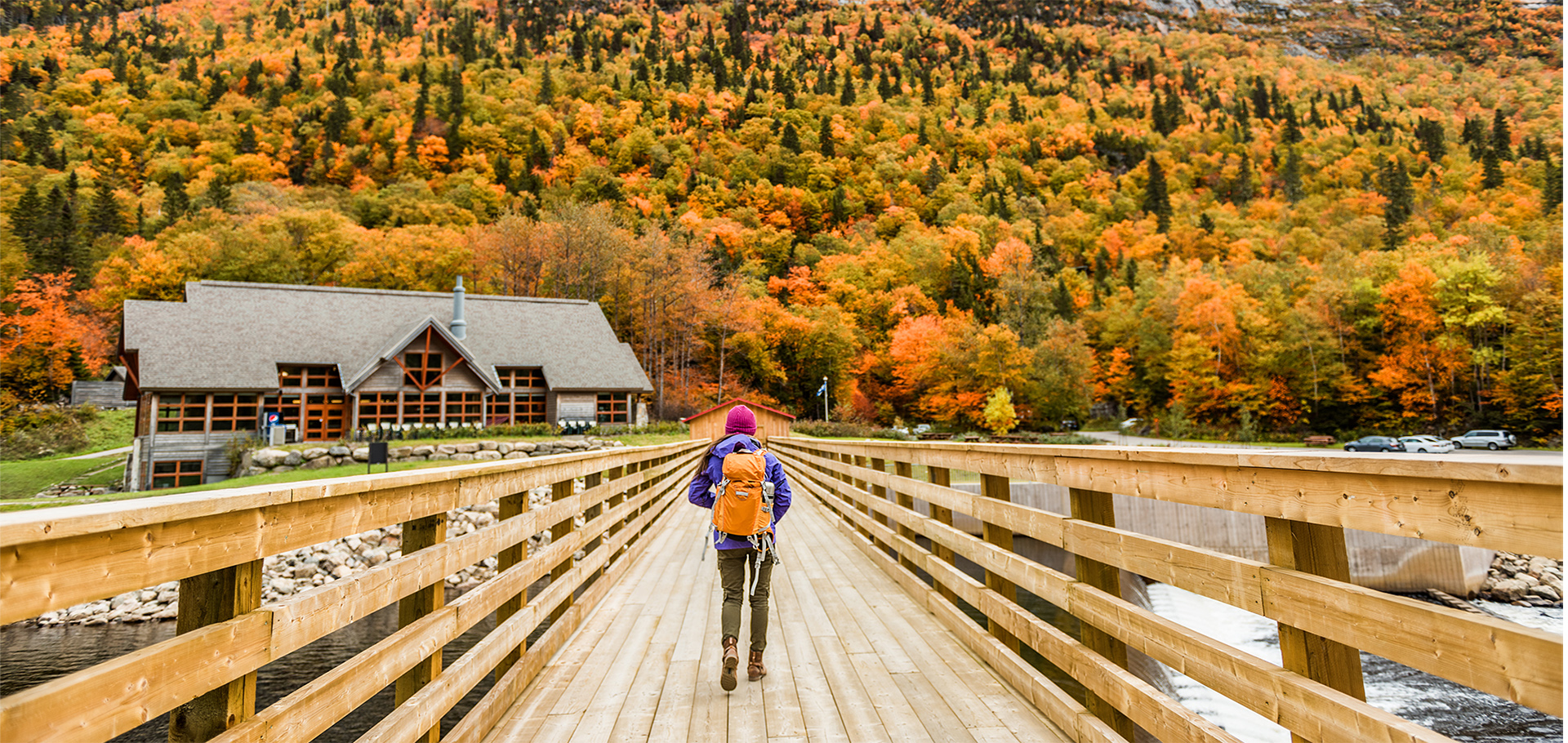 Autumn nature hiker girl walking in national park in Quebec with backpack. Woman tourist going camping in forest. Canada travel hiking tourism at Hautes-Gorges-de-la-Riviere-Malbaie National Park.
