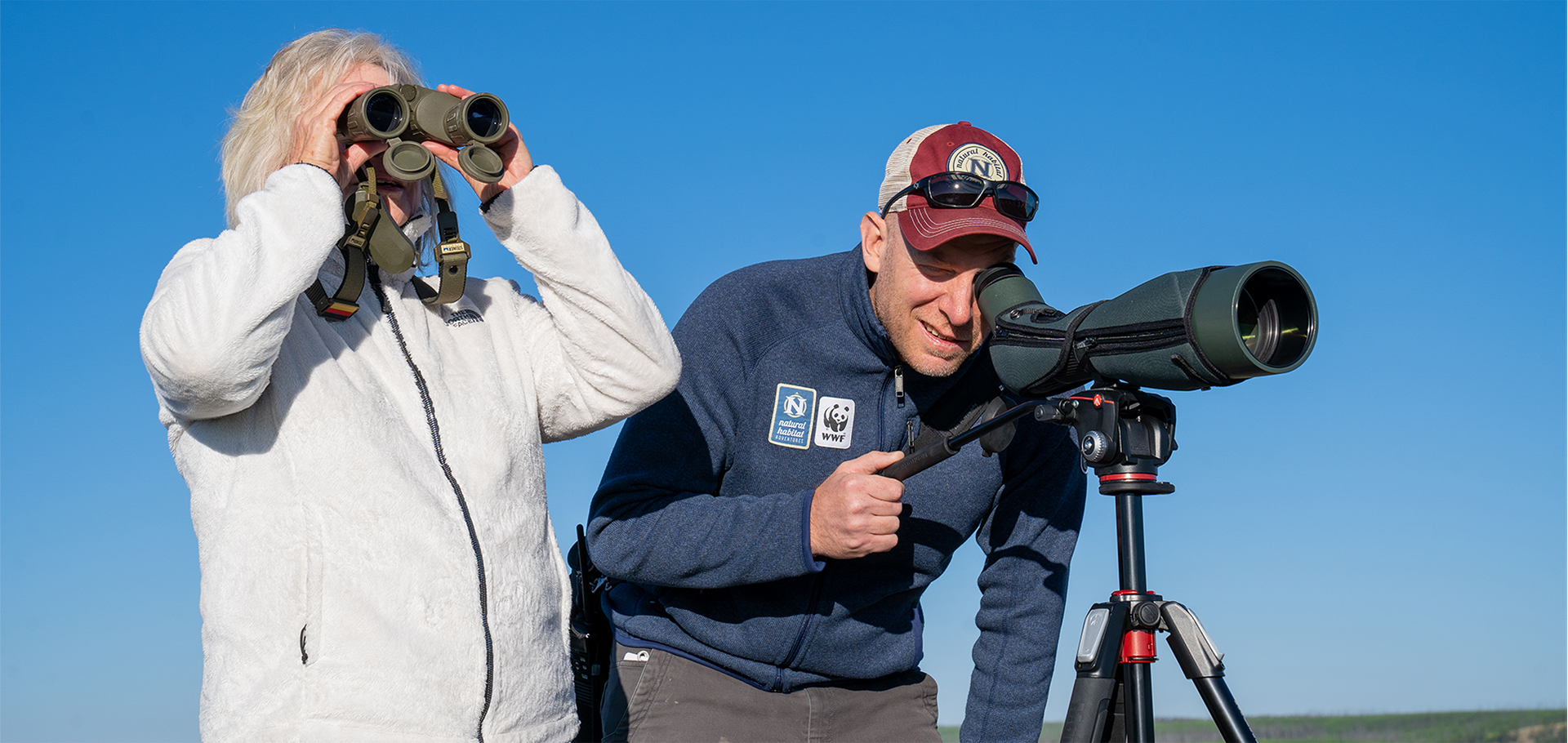 Nat Hab guide and traveler using binocular and scope in Yellowstone National Park Lamar Valley wildlife spotting safari