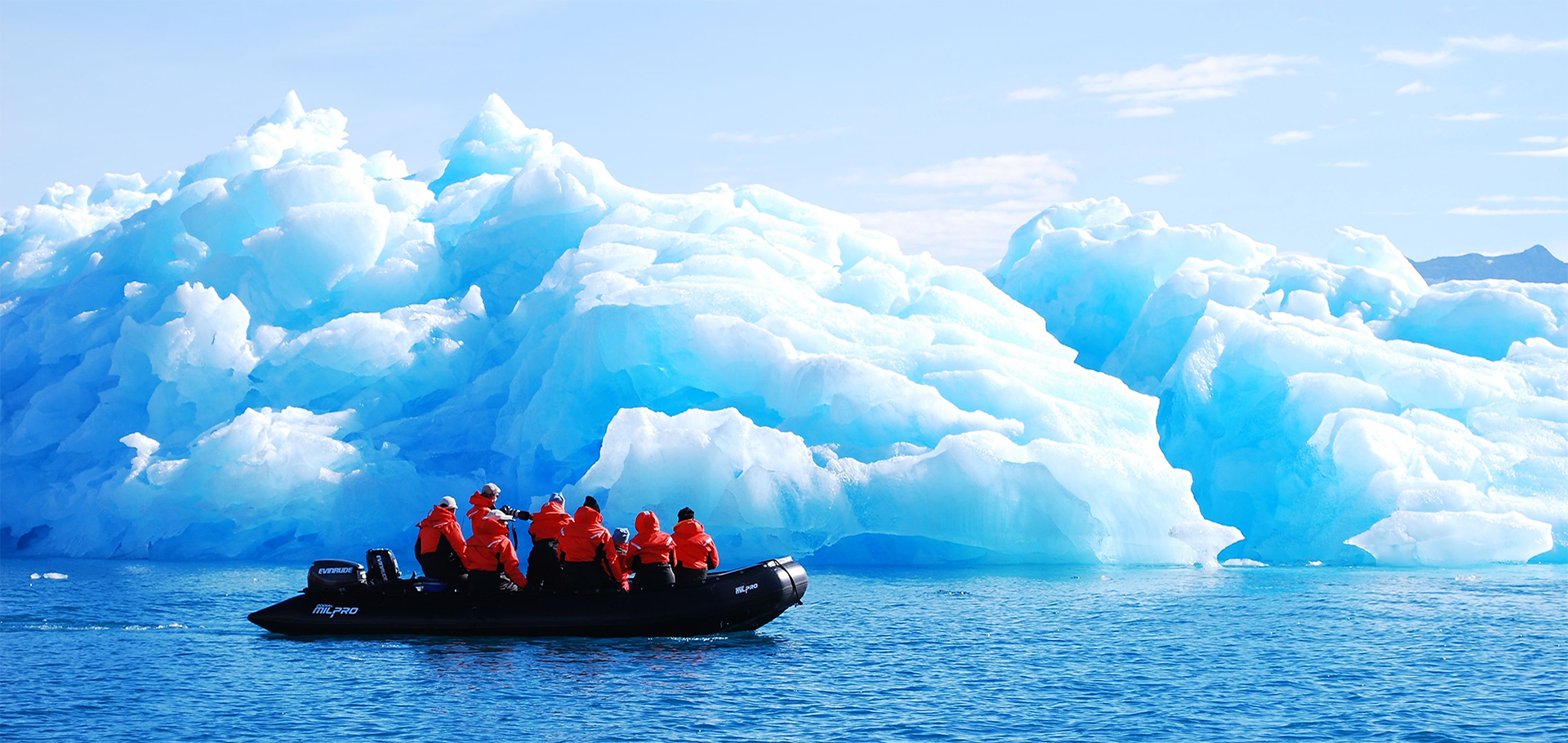 Natural Habitat Adventures & WWF travelers ride a private zodiac boat into the Arctic waters of Greenland to photograph ice floes and glaciers climate change exploration sustainable travel