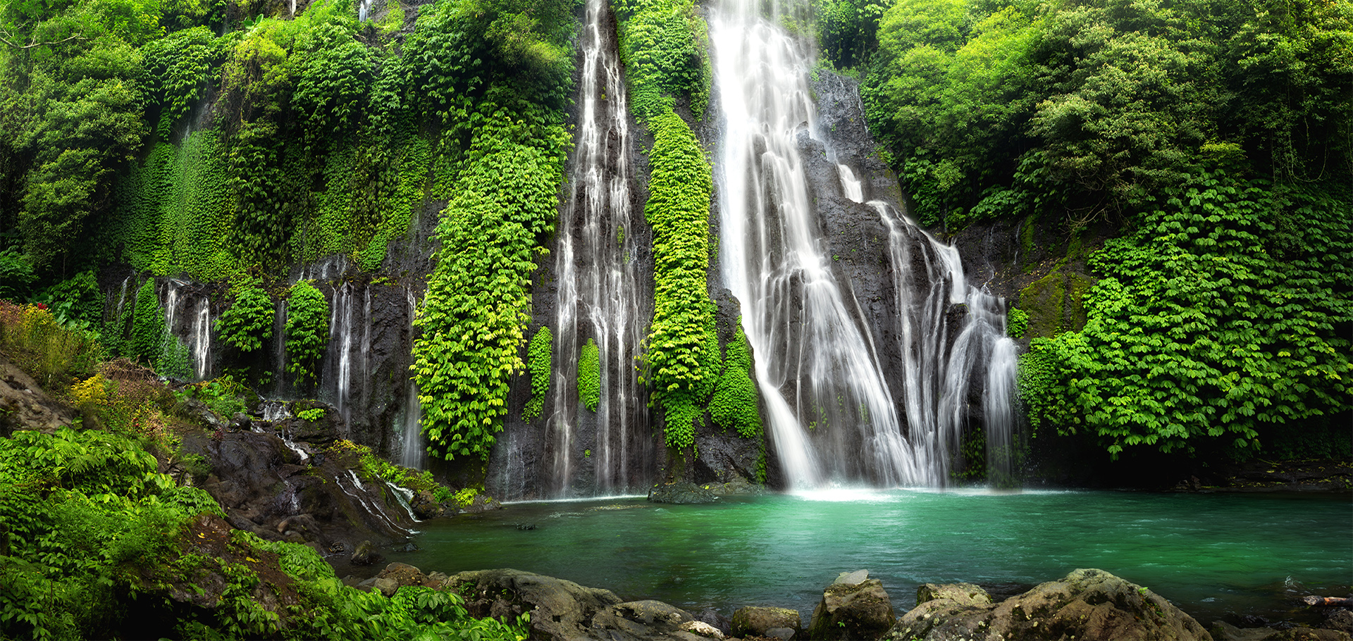 Jungle waterfall cascade in tropical rainforest with rock and turquoise blue pond. Its name Banyumala because its twin waterfall in mountain slope