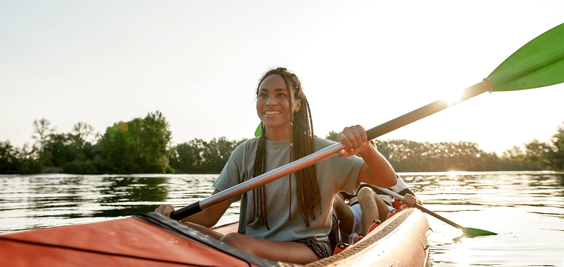 Active young Black woman smiling, enjoying a day kayaking together with her boyfriend in a lake on a late summer afternoon. Kayaking, travel, leisure concept.