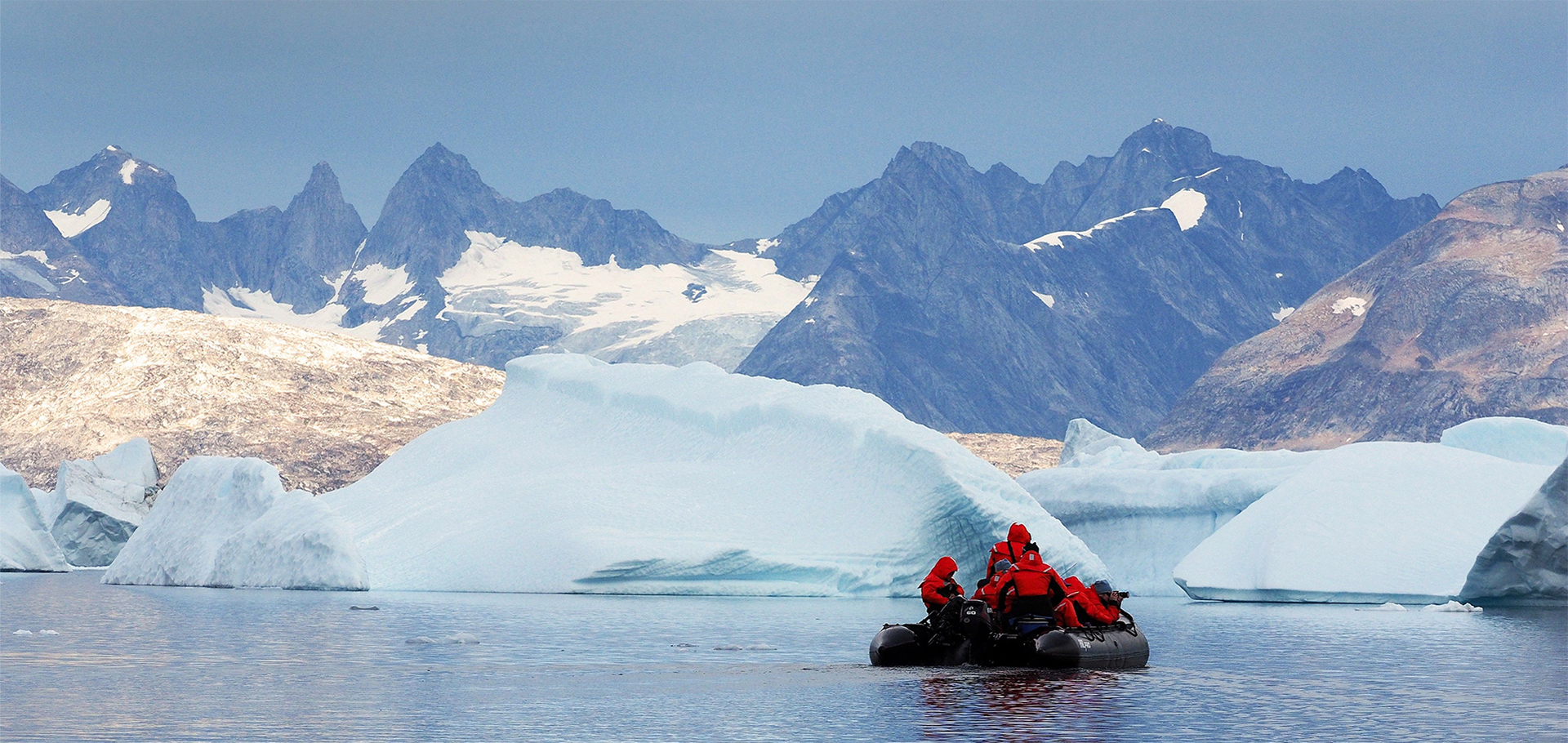 Calm arctic waters in Greenland as zodiac glides through fjords of glaciers and icebergs Zodiac boat ride wildlife tour nature travel conservation climate change solutions