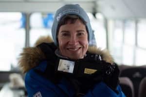 Older woman traveler smiles proudly as she shows photo of polar bear she took while on nature tour in Churchill Canada