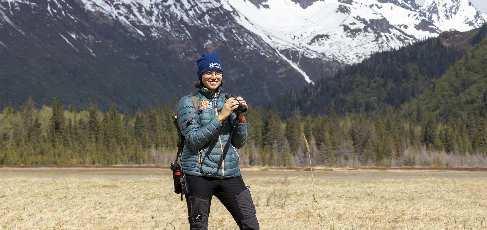 Female expedition leader and wildlife guide for natural habitat adventures and WWF holds binoculars in Alaska wild