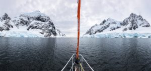 Panoramic view of sailboat bow or prow in the famous Lemaire Channel in the Antarctic Peninsula. Surrounded by mountains and glaciers while sailing in Antarctica