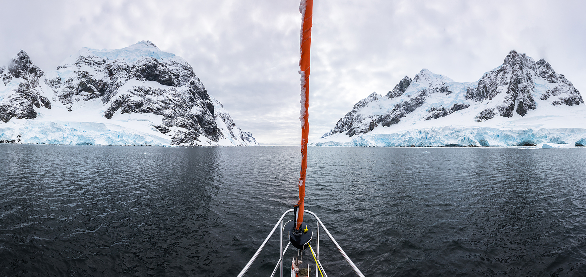 Panoramic view of sailboat bow or prow in the famous Lemaire Channel in the Antarctic Peninsula. Surrounded by mountains and glaciers while sailing in Antarctica