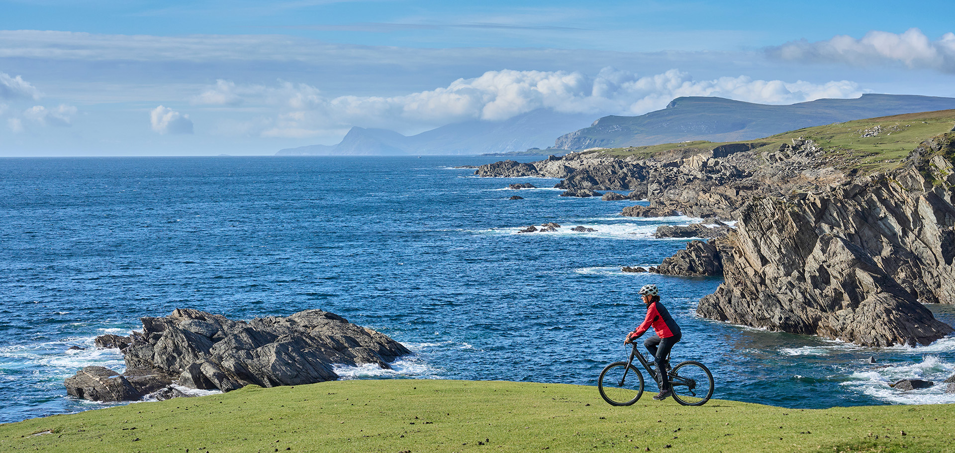 nice senior woman on mountain bike, cycling on the cliffs of Achill Island, Carrowgarve, Republik of Ireland