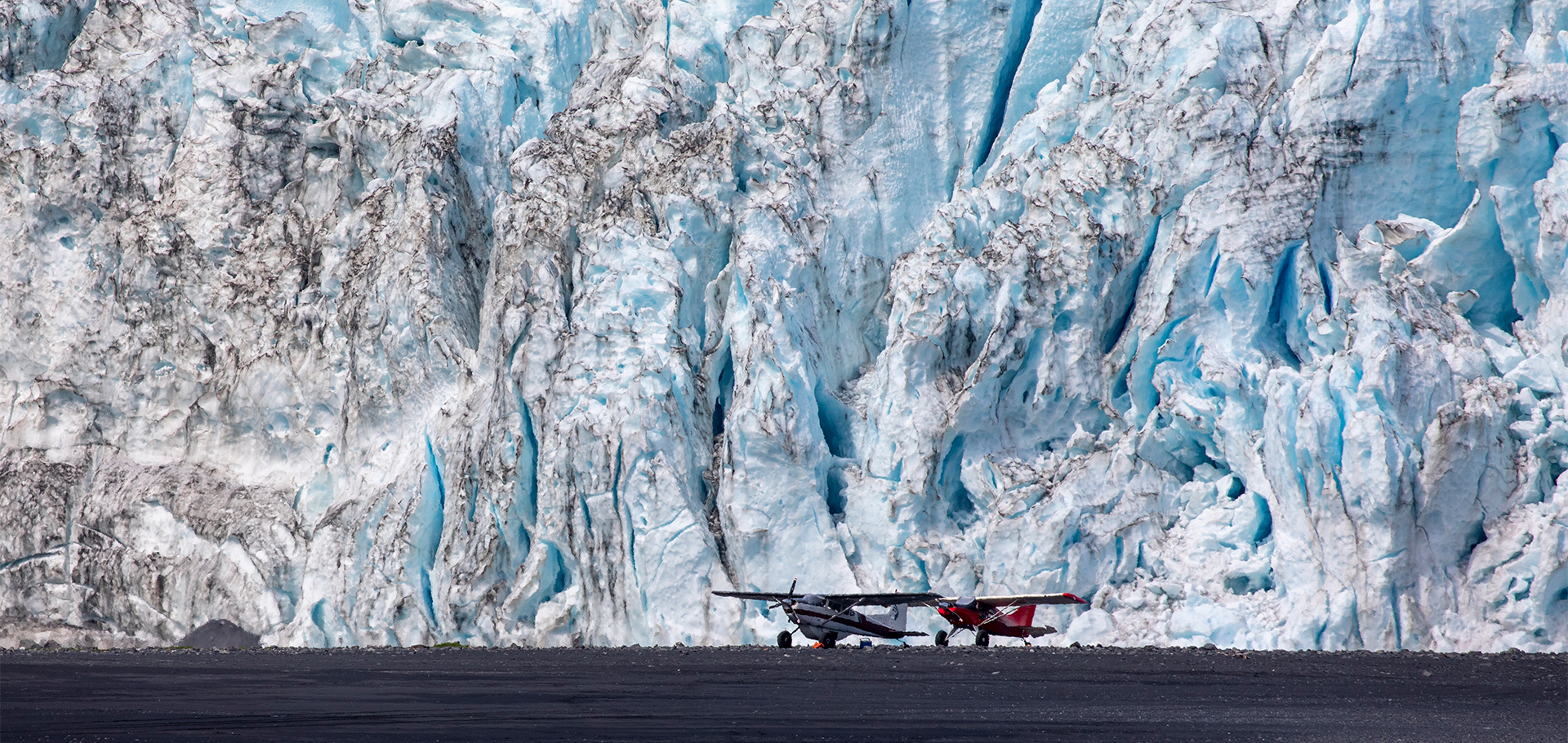 two charter air planes in Alaska on beach with glaciers in the background
