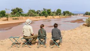 Family of father and kids on African safari vacation enjoying Ewaso Nyiro River views in Samburu Kenya