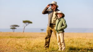 Family of father and child on African safari vacation enjoying bush view
