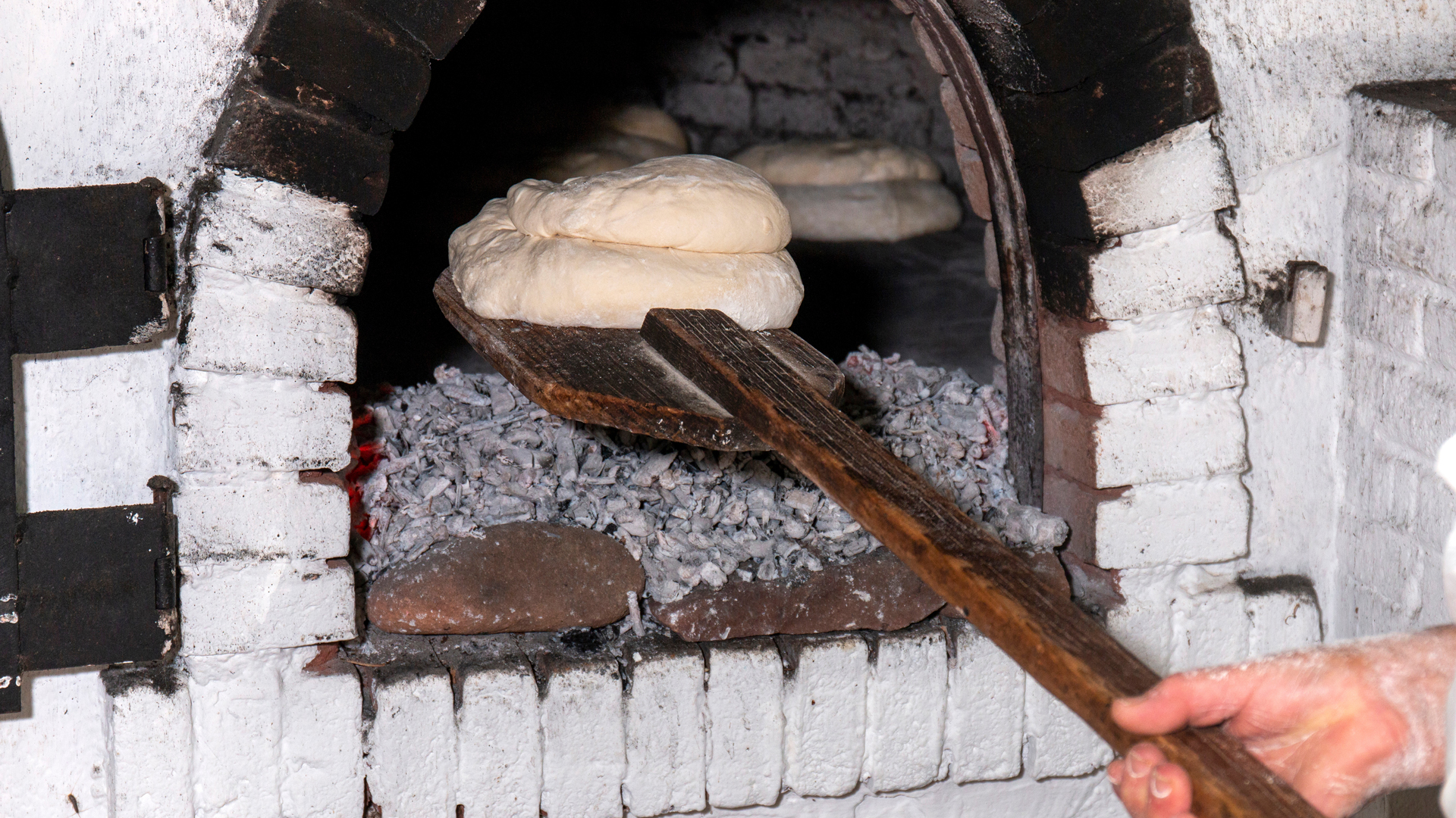 traditional rustic bread enters stone charcoal oven to cook.