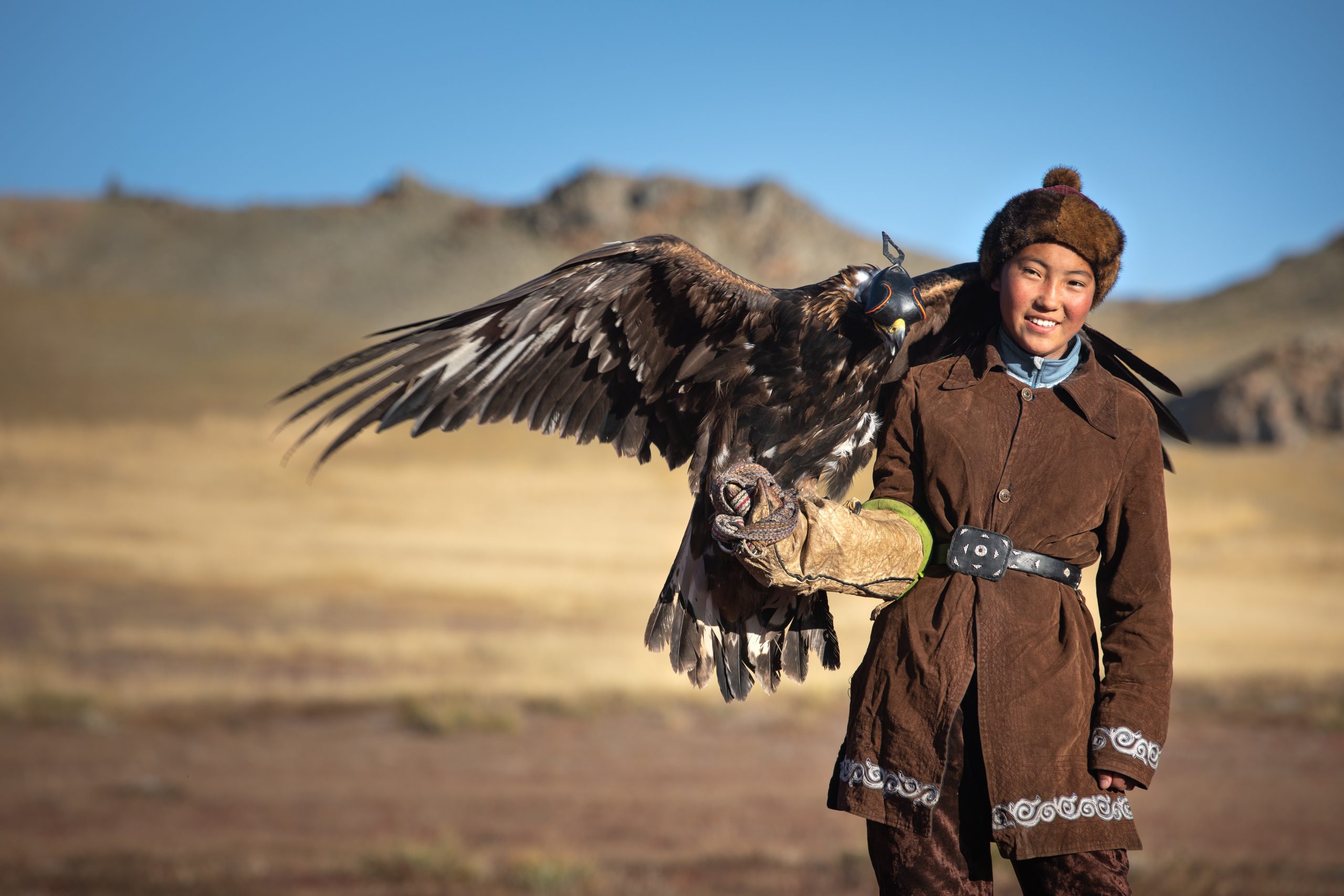Traditional kazakh eagle hunter girl with his golden eagle that is used to hunt for fox and rabbit fur. Ulgii, Western Mongolia.