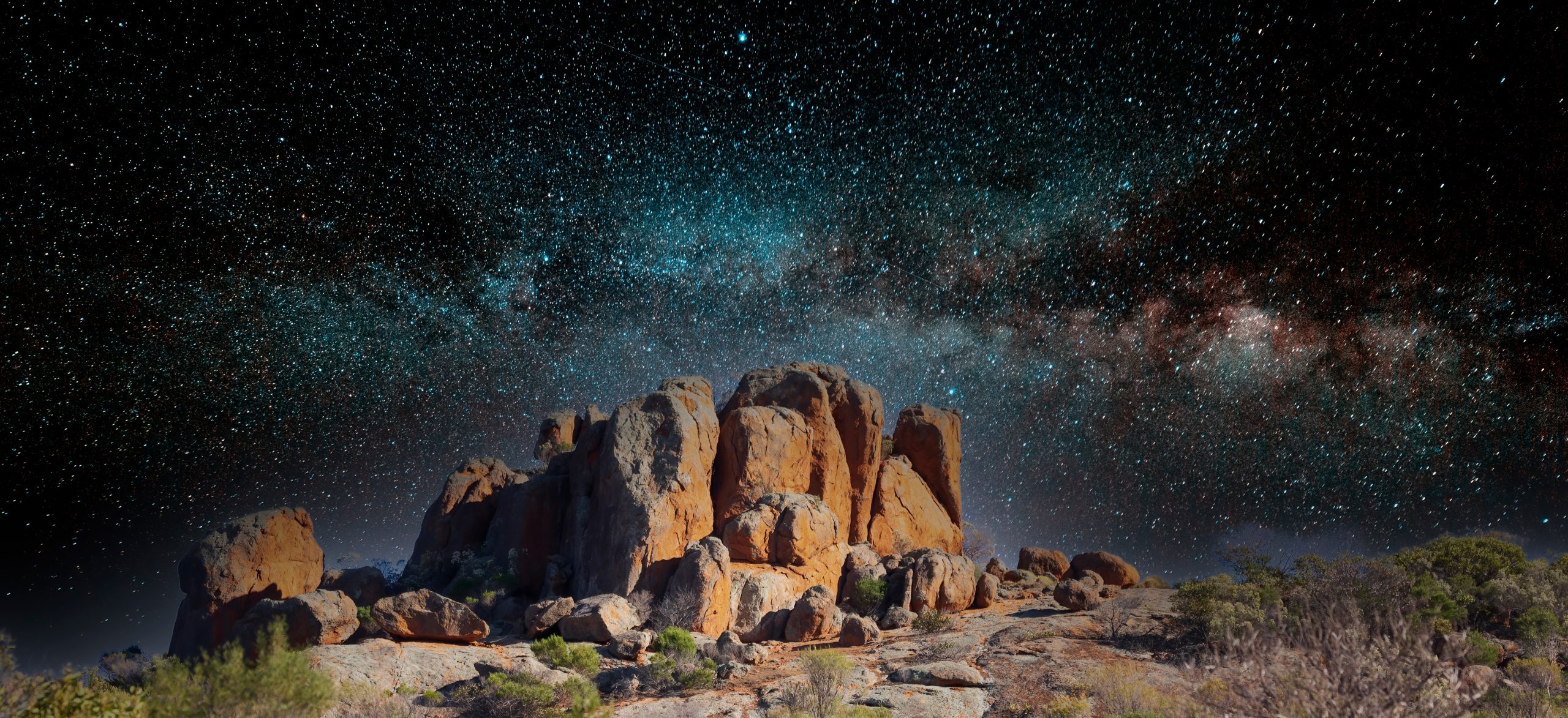 Merged image of a rocky outcrop among other rocks in the Australian outback with an image of a starry sky